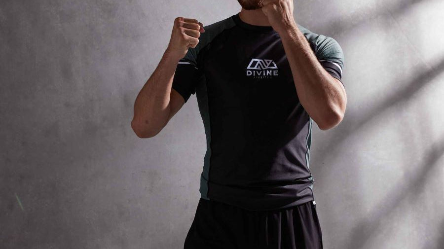 Man in a muay thai stance. he is wearing a bjj rashguard and shorts.