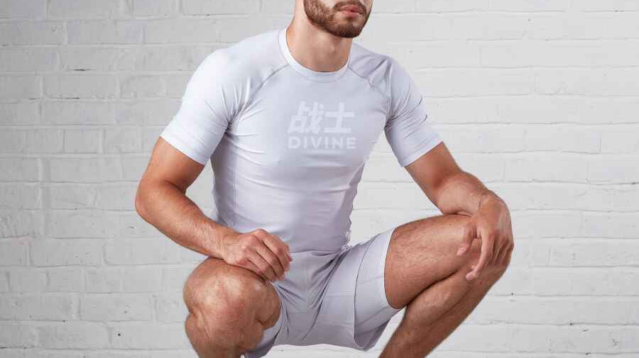 Man kneeling down showing off a grey rashguard