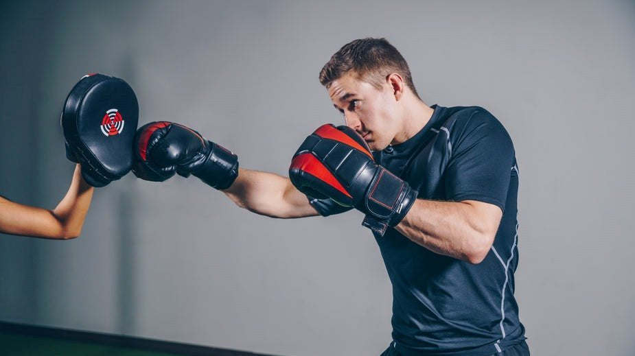 man in the picture is a kickboxer. he is punching into a hand pad.