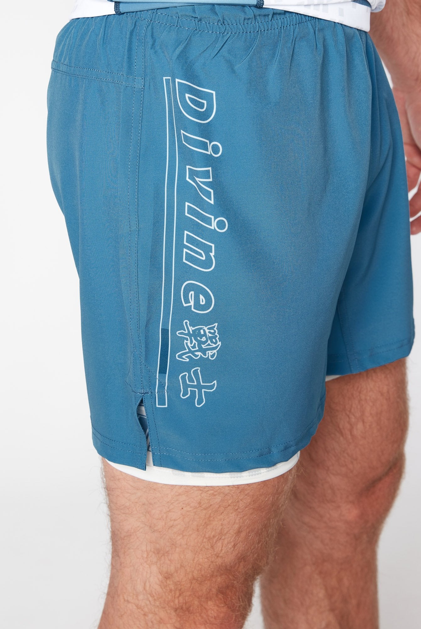 Side view of blue NoGi BJJ shorts with white compression liner underneath – dual-layer MMA training shorts featuring elastic waistband and modern athletic fit.