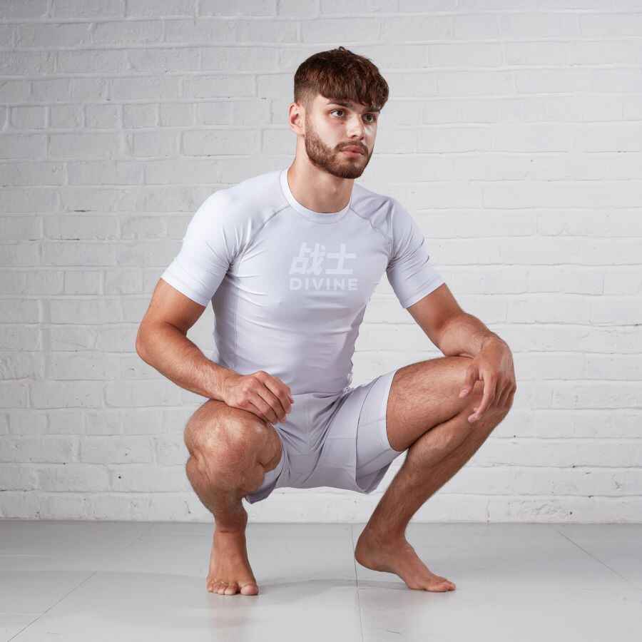 Man kneeling down showing off a grey rashguard