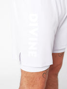 Close-up of a white shirt with "DIVINE" text and a glimpse of tattooed arms.